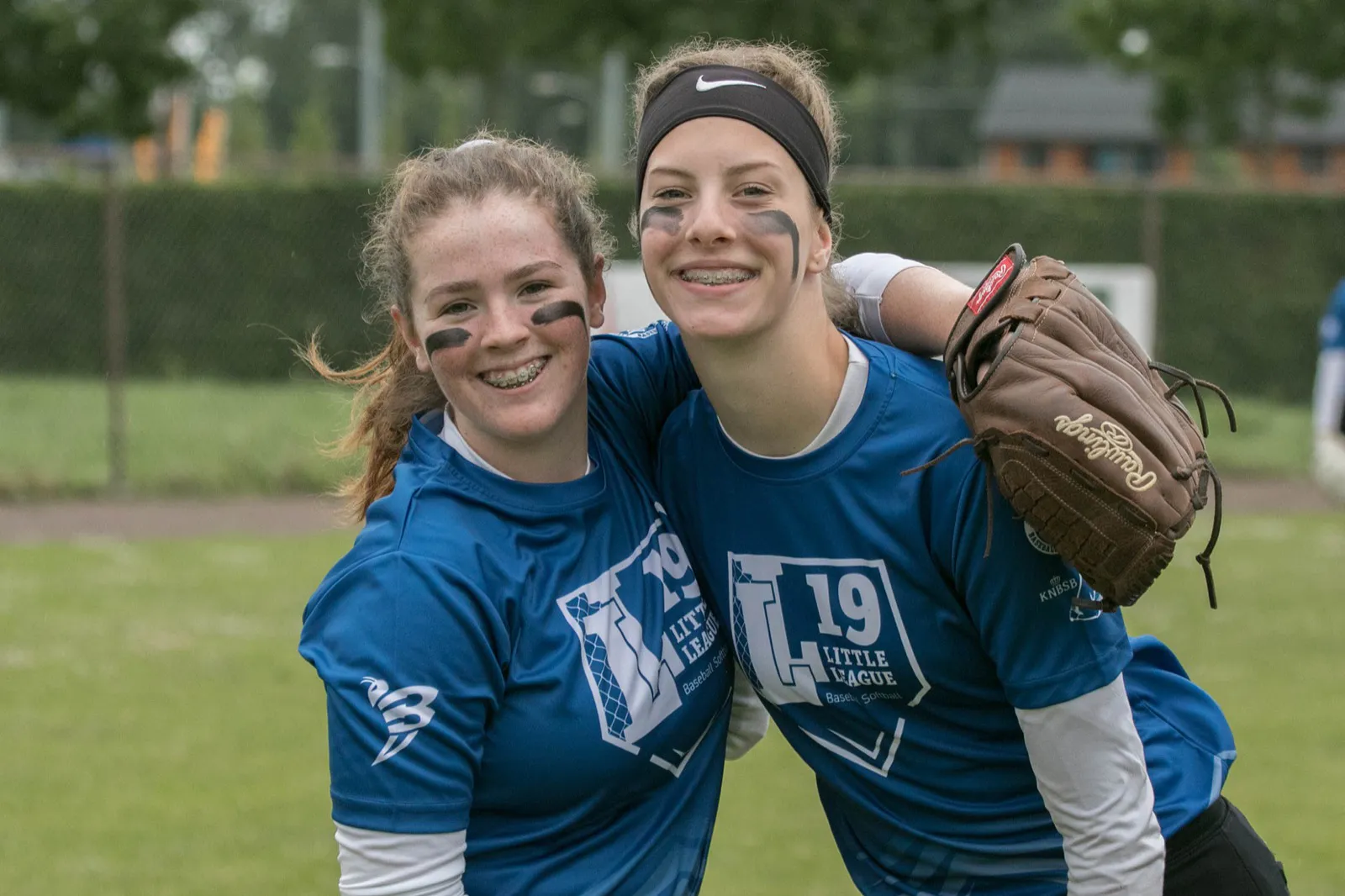 Twee softbalspeelsters met een arm om elkaar heen op het veld tijdens het NK Little League 2019.