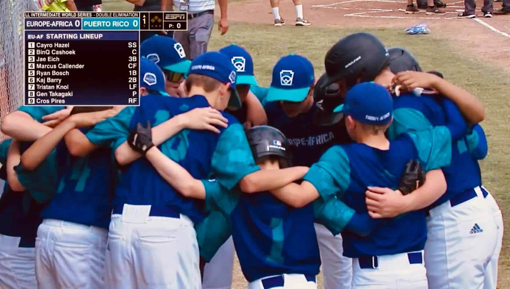 Jeugdhonkballers van Europe-Africa in blauwe shirts staan in een kring tijdens de Intermediate World Series tegen Puerto Rico.