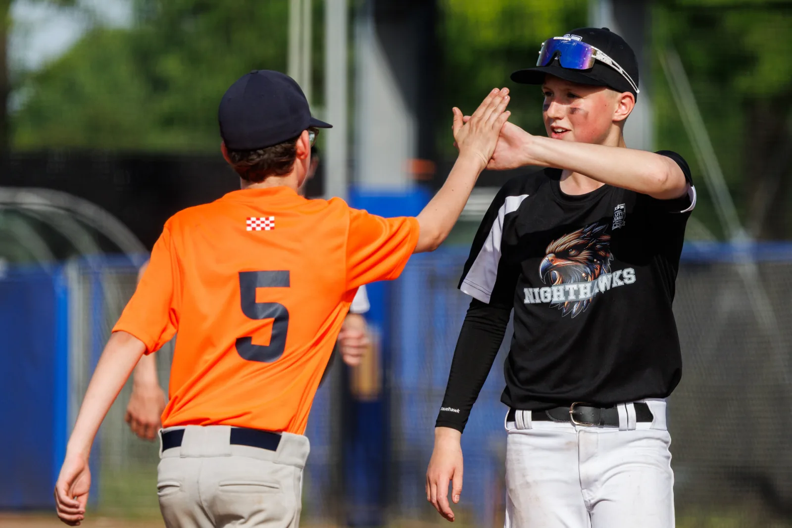 Twee spelers in tegengestelde tenues geven elkaar een high five op het veld.
