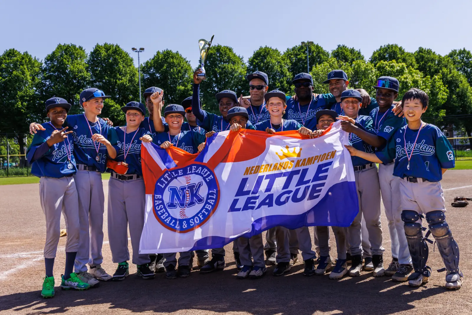 Een kampioensteam poseert achter de vlag Nederlands Kampioen Little League.