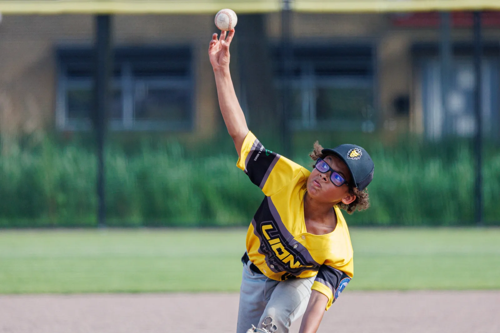 Pitcher in het geel-zwarte shirt van de Lions haalt uit voor een worp.