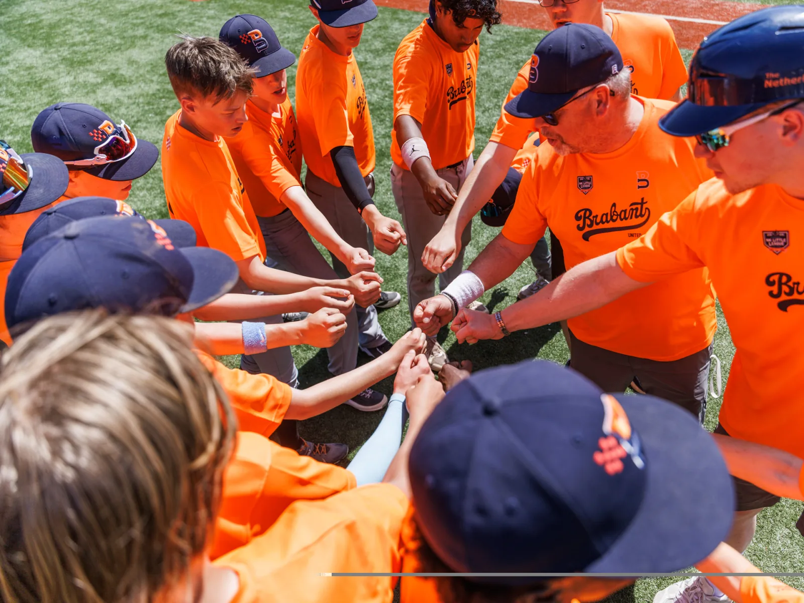 Spelers en coach leggen hun vuisten in het midden voor de wedstrijd.