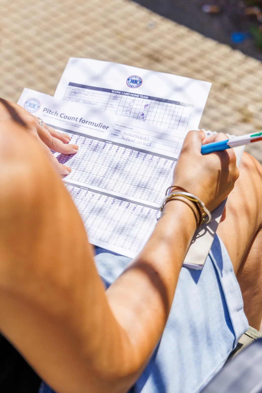 Handen vullen met pen het pitch count-formulier in.