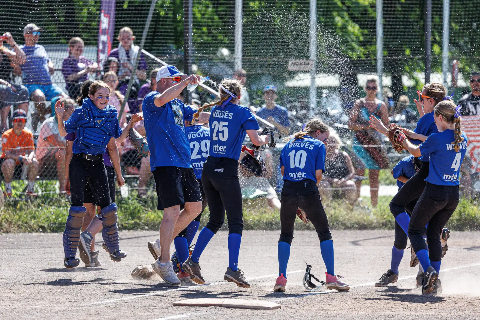 Softbalteam viert de overwinning bij de thuisplaat en gooit water in de lucht