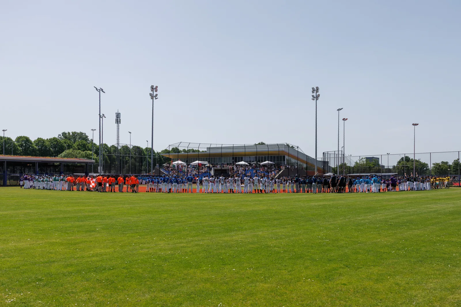 Alle deelnemende teams staan in een lange rij langs het binnenveld tijdens de opening van het toernooi.