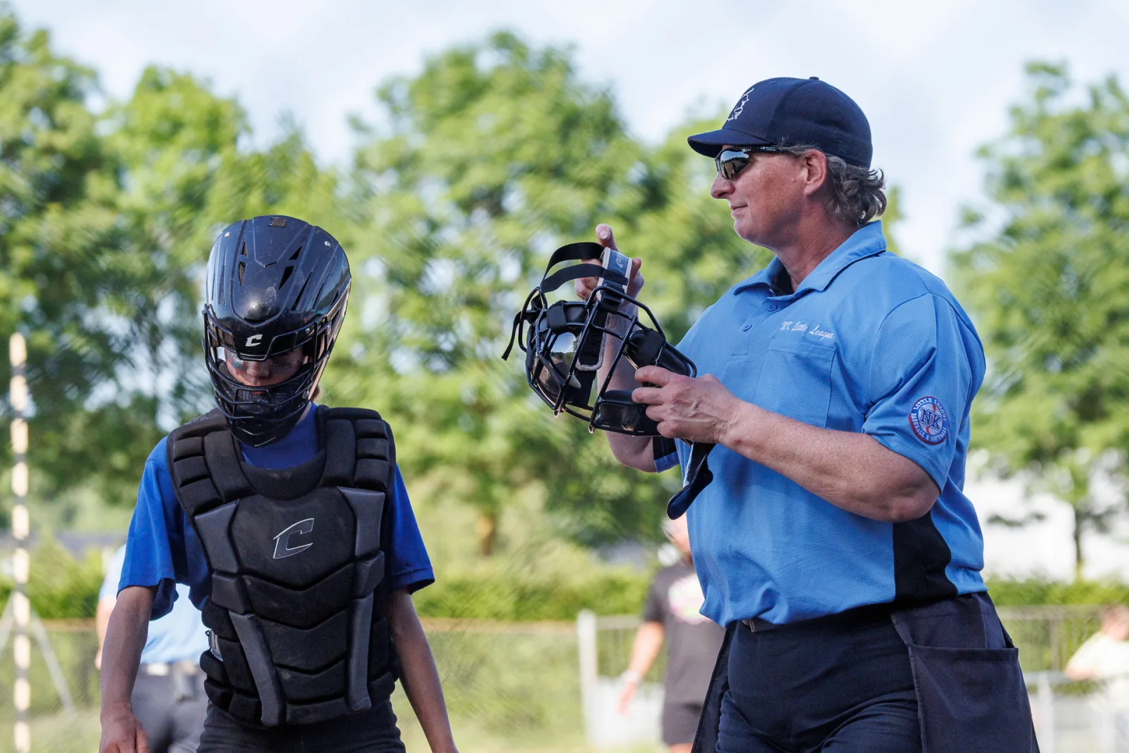 Een umpire houdt het masker vast en overlegt met de catcher.