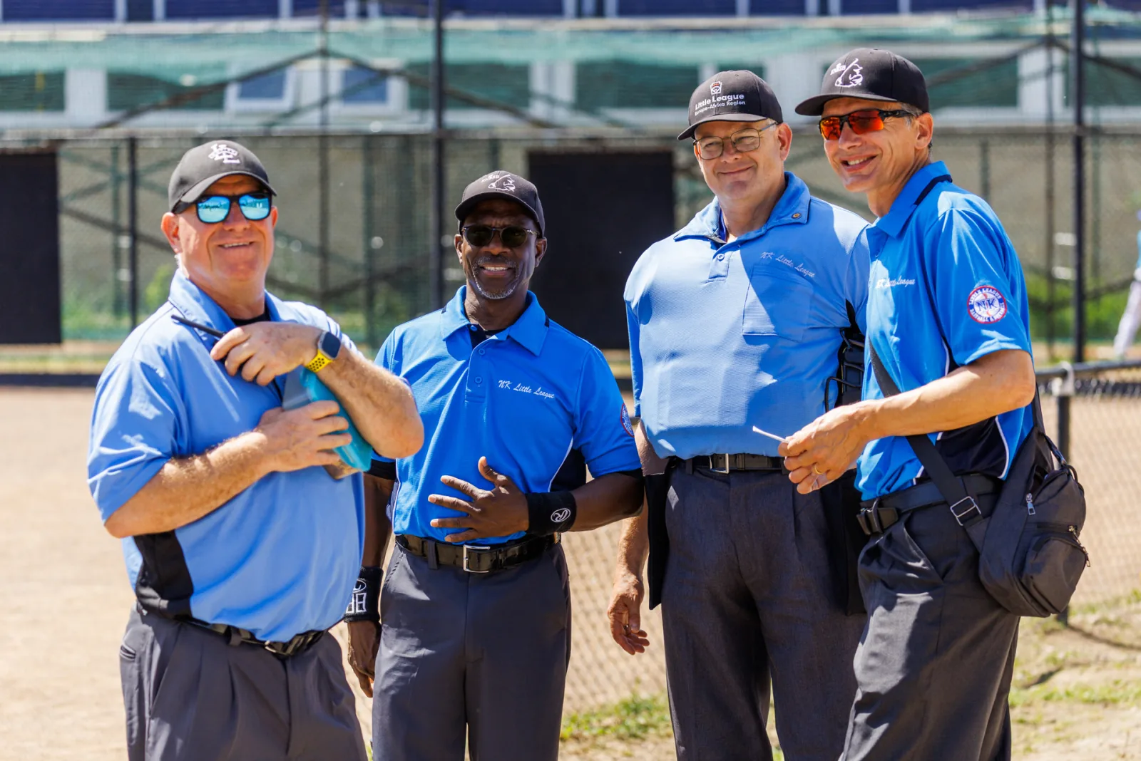 Vier umpires staan lachend te overleggen langs de kant van het veld.