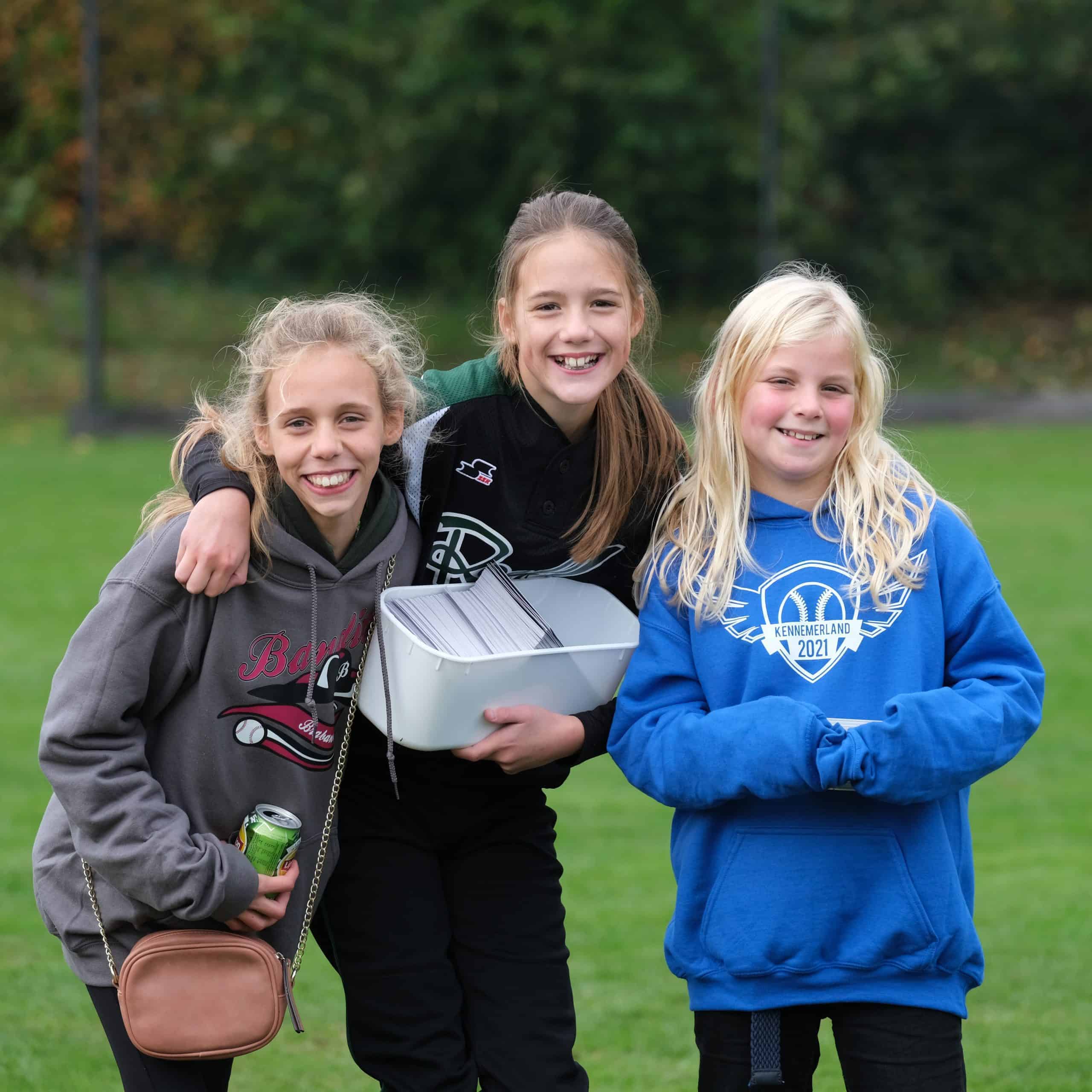 Vrolijke jonge meisjes op een Little League softball veld tijdens een jeugdtoernooi.