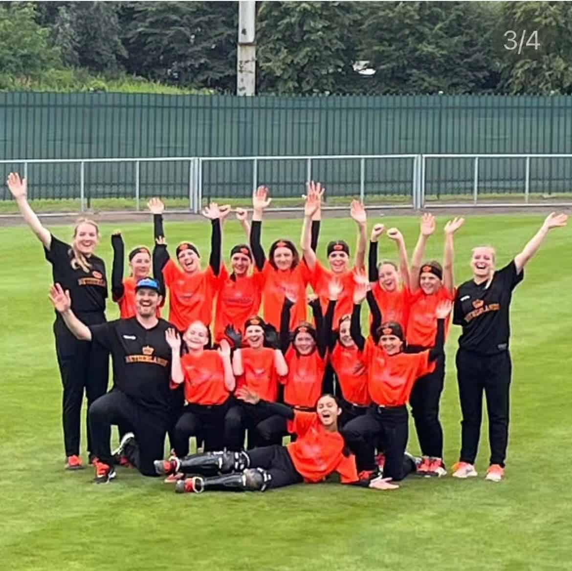 Vrijwilligers en spelers van Little League in een teamfoto op het veld.