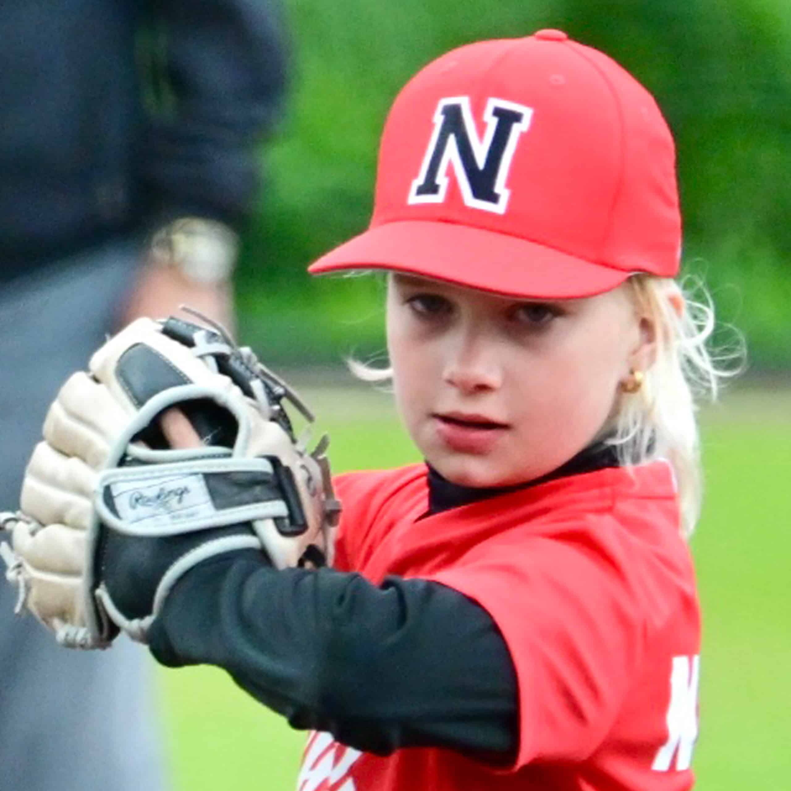 Kinderspeler in Little League softball, gericht op plezier en ontwikkeling, gekleed in sportkleding en baseballcap.
